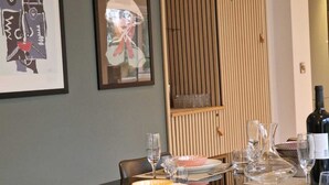 Un coin repas avec une table dressée pour deux personnes, agrémenté d’une bouteille de vin, de verres et d’assiettes.
