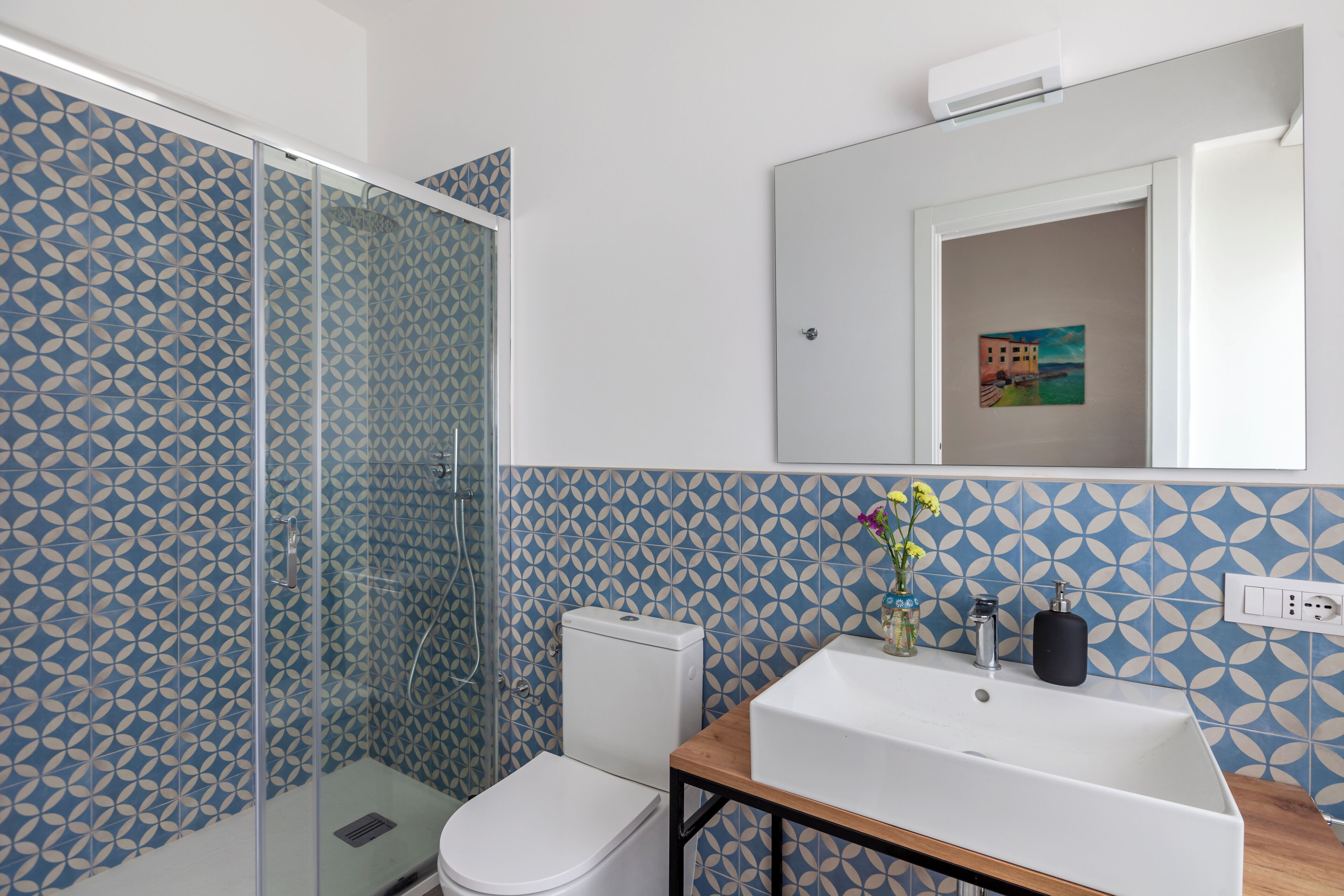 A bathroom with a shower, toilet, sink, and a mirror.