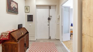 A hallway with a wooden cabinet, a patterned rug, and a door leading to a bedroom.