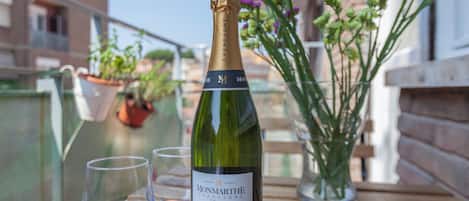 En flaske Monmarthe champagne på et træbord med to tomme glas og en vase med blomster.