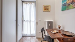 A room with a wooden table, a chair, a radiator, and a painting on the wall.