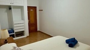 A bedroom with a bed, a ceiling fan, a wardrobe, and a door.