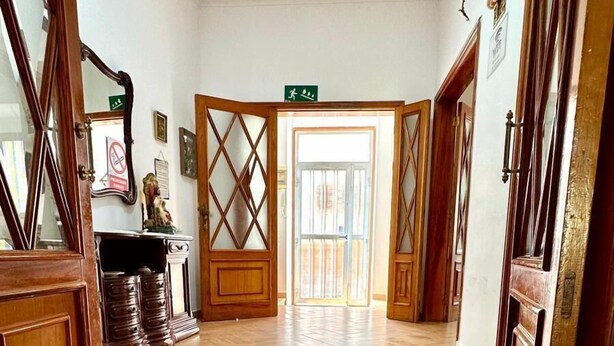 A spacious hallway with wooden flooring and a large glass door leading to an outdoor area.