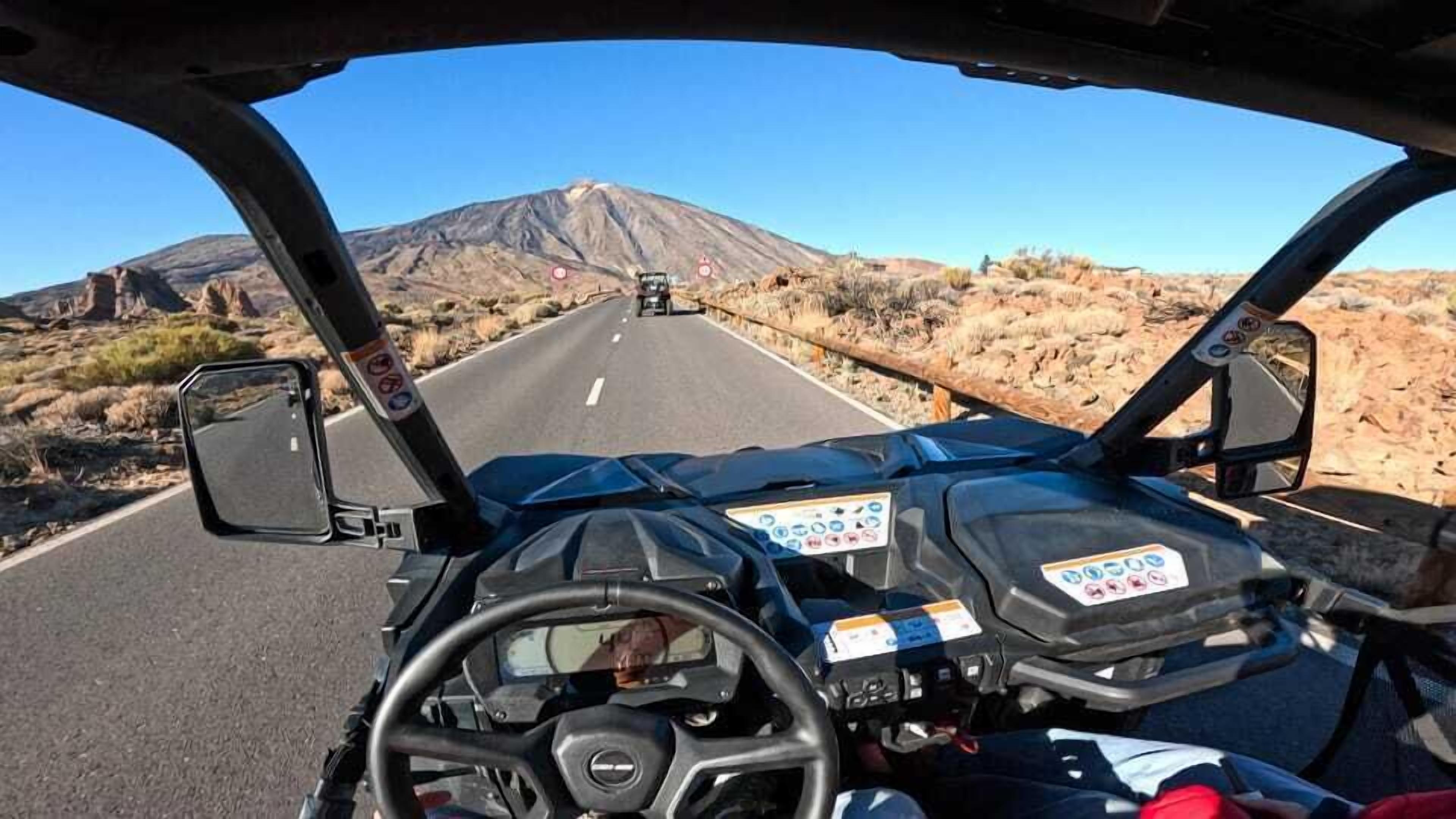 A vehicle's interior with a steering wheel, dashboard, and side mirrors.