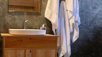 A bathroom with a wooden vanity, a sink, a mirror, and two towels hanging on the wall.