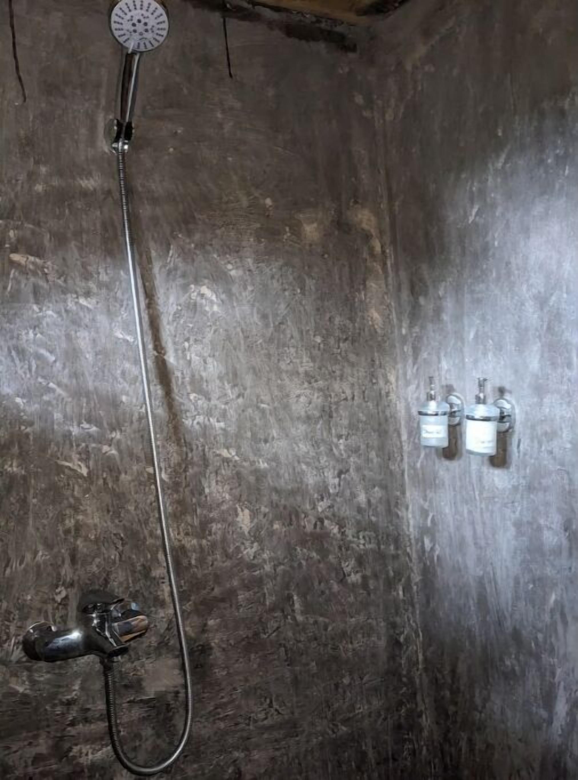 A shower with a handheld showerhead and a handheld faucet.