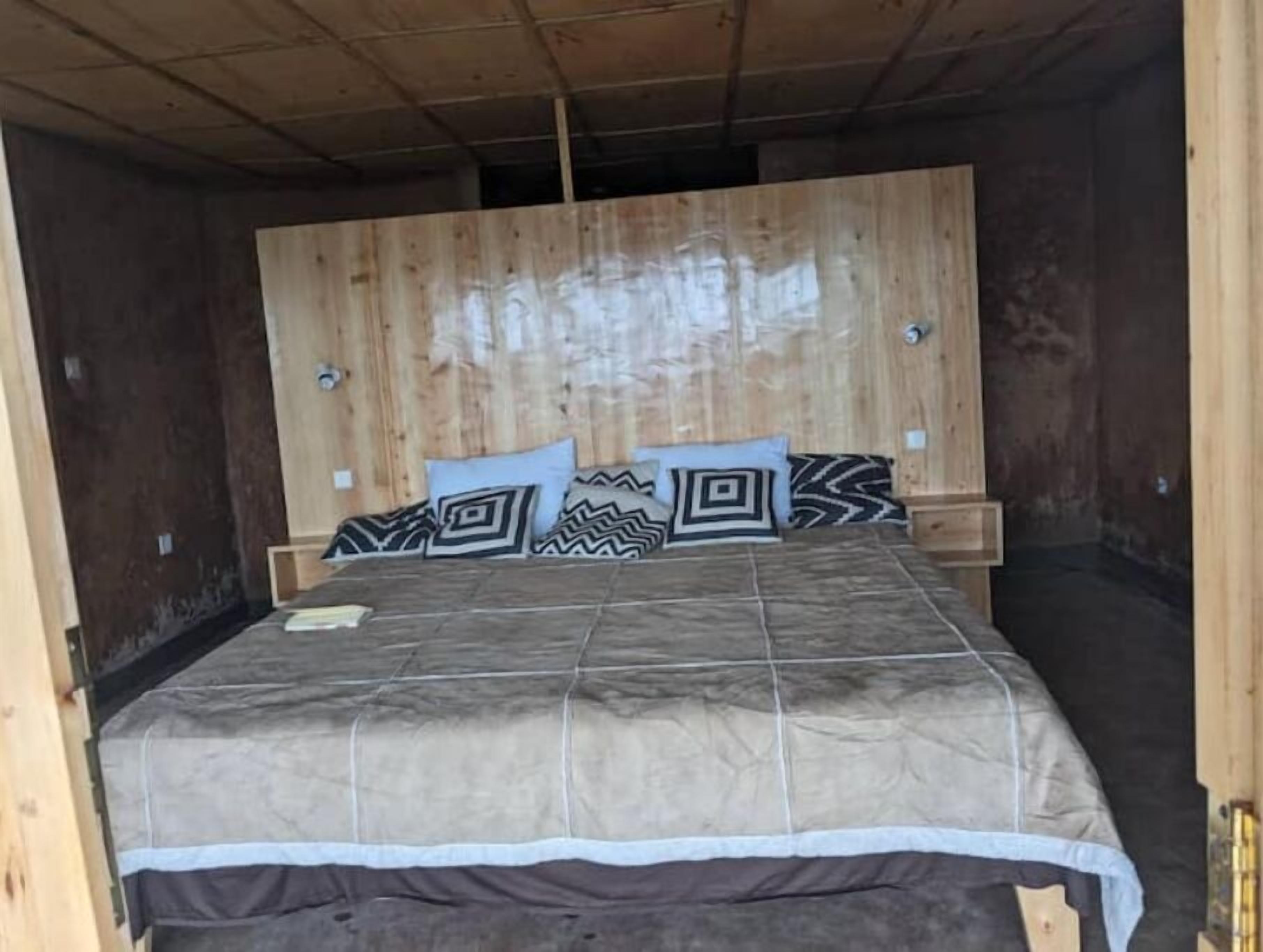 A wooden-paneled bedroom with a bed, pillows, and bedside tables.