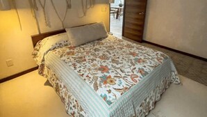 Ein Schlafzimmer mit Bett, Deckenventilator und einer Tür, die auf einen Balkon führt.