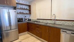 Eine moderne Küche mit Edelstahlgeräten, Holzschränken und einer ornamentierten Spritzschutzleiste.