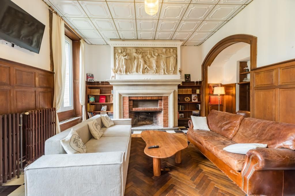 A cozy living room with a fireplace, a sofa, a coffee table, and a television mounted on the wall.