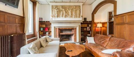 A cozy living room with a fireplace, a sofa, a coffee table, and a television mounted on the wall.