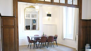A dining area with a checkered floor, wooden furniture, and a large mirror. - La Royale Jacuzzi Sauna Jardin Gare - Hôtel Lefort (Guingamp)
