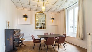 A dining area with a piano, a large mirror, and a herringbone-patterned floor. - La Royale Jacuzzi Sauna Jardin Gare - Hôtel Lefort (Guingamp)