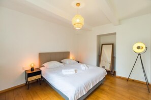 A bedroom with a bed, bedside tables, a hanging light fixture, and a floor lamp.