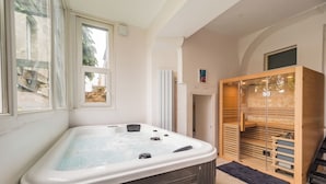A spa room with a hot tub, wooden sauna, and a view of the outside. - La Royale Jacuzzi Sauna Jardin Gare - Hôtel Lefort (Guingamp)