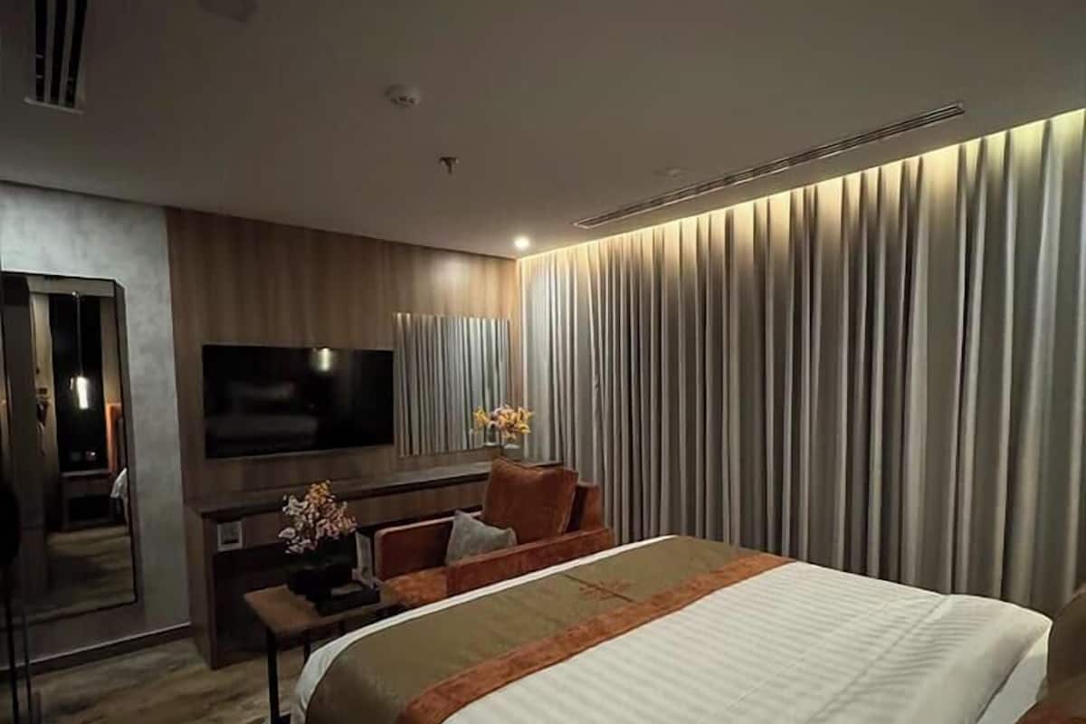 Una habitación de hotel moderna con una cama grande, un televisor de pantalla plana, un escritorio con silla y un sofá.