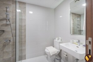 A modern bathroom with a glass shower enclosure, a toilet, and a sink with a mirror above it.