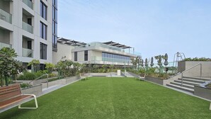 A modern building with a flat roof, a grassy courtyard, and a staircase leading to an upper level. - Brand New with Relaxing Pool & Kids Area (Dubai)