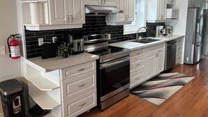 A modern kitchen with white cabinetry, a stainless steel range, and a black tiled backsplash.