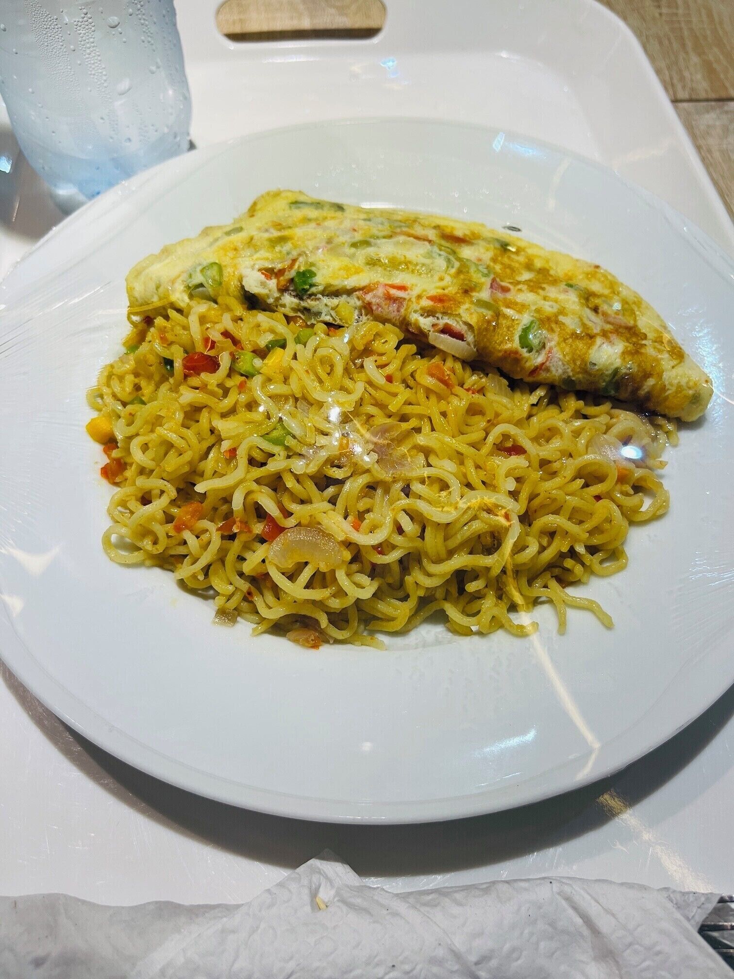 A plate of food with noodles and a piece of omelette.