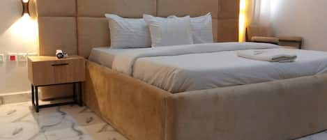 Un dormitorio con una cama grande, una mesita de noche, una lámpara de pared y un cuadro en la pared.
