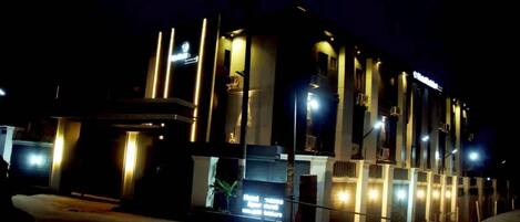 A modern building with a prominent vertical design, illuminated by street lighting.