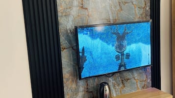 Una sala moderna con un televisor de pantalla plana montado en una pared de mármol, mueble de entretenimiento de madera debajo y paneles acústicos negros a los lados.