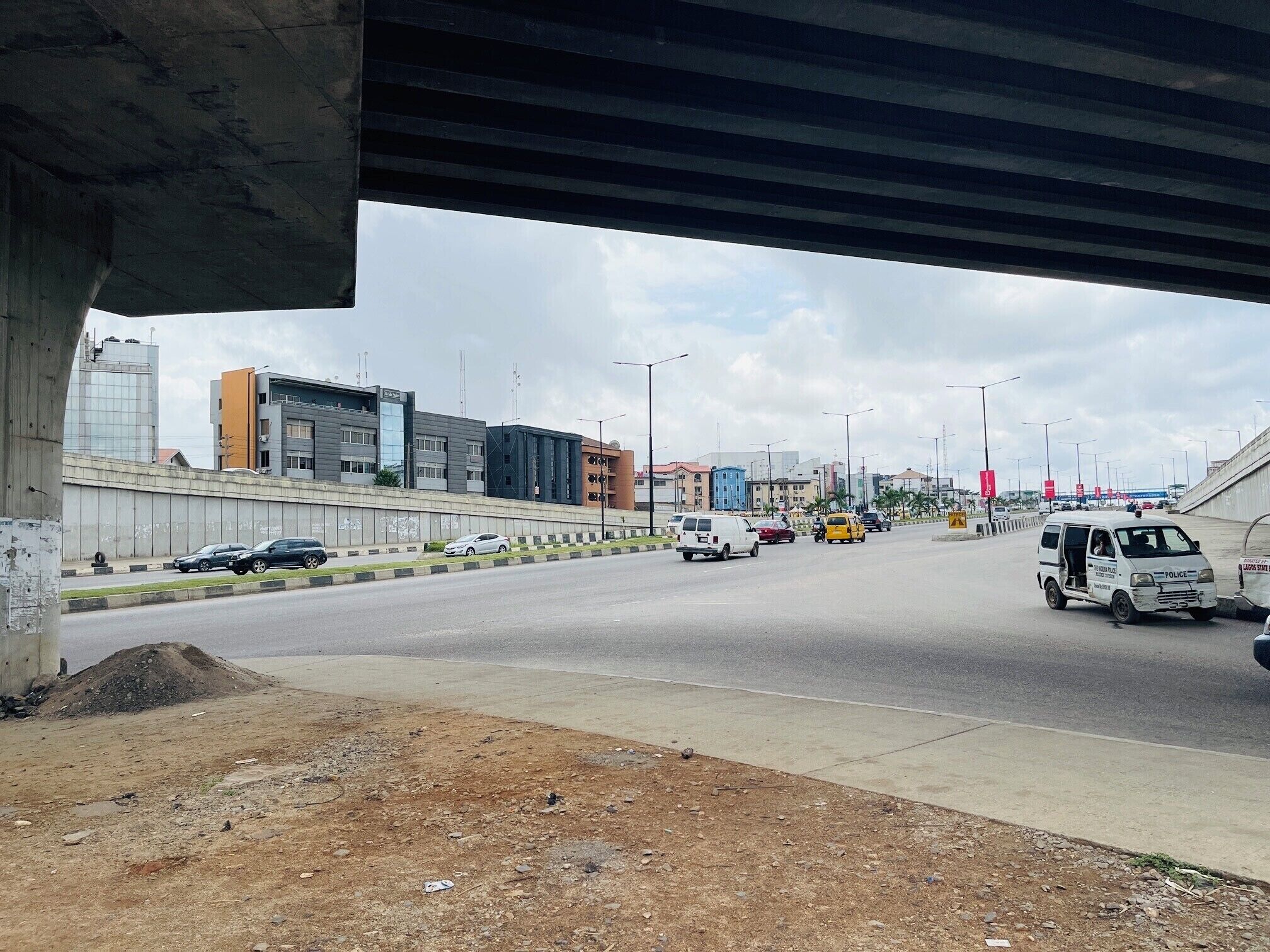 A multi-lane road with vehicles, including a police van, under a bridge.