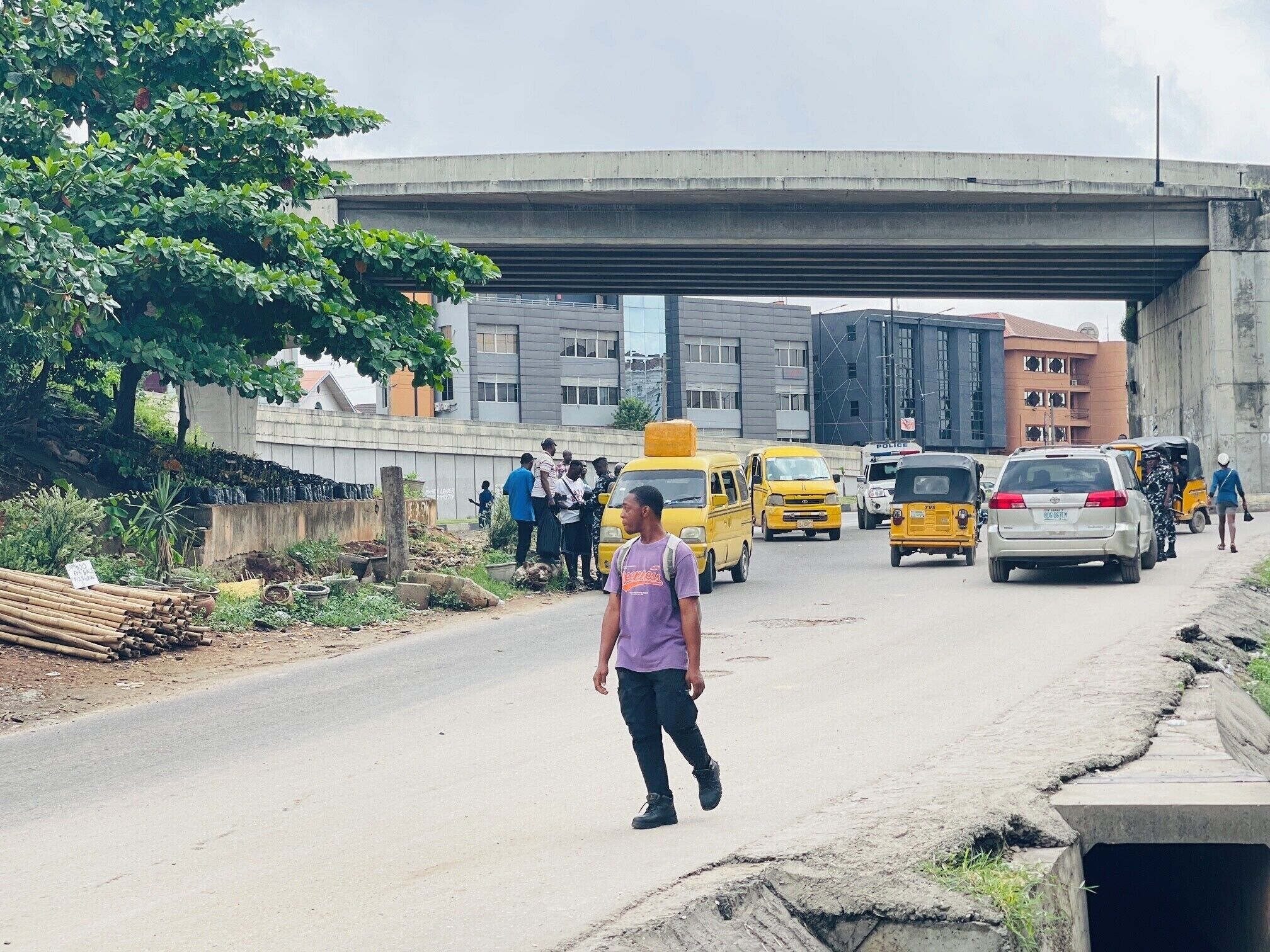 Une rue animée en milieu urbain, avec des véhicules, des piétons et des bâtiments situés sous un pont.