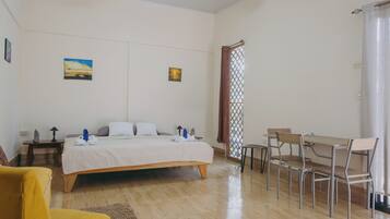 A bedroom with a bed, bedside tables, a desk with chairs, and a window with a curtain.