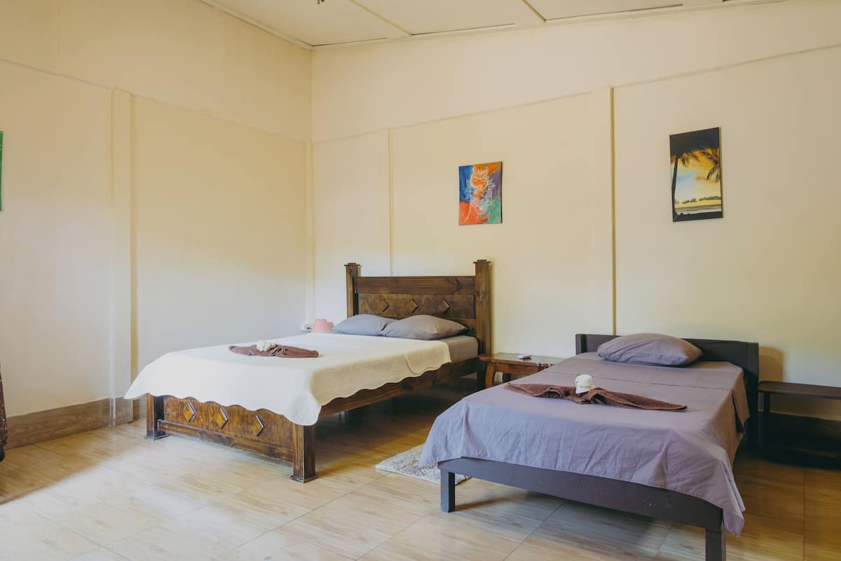 A bedroom with two wooden beds, a small bedside table, and a nightstand.