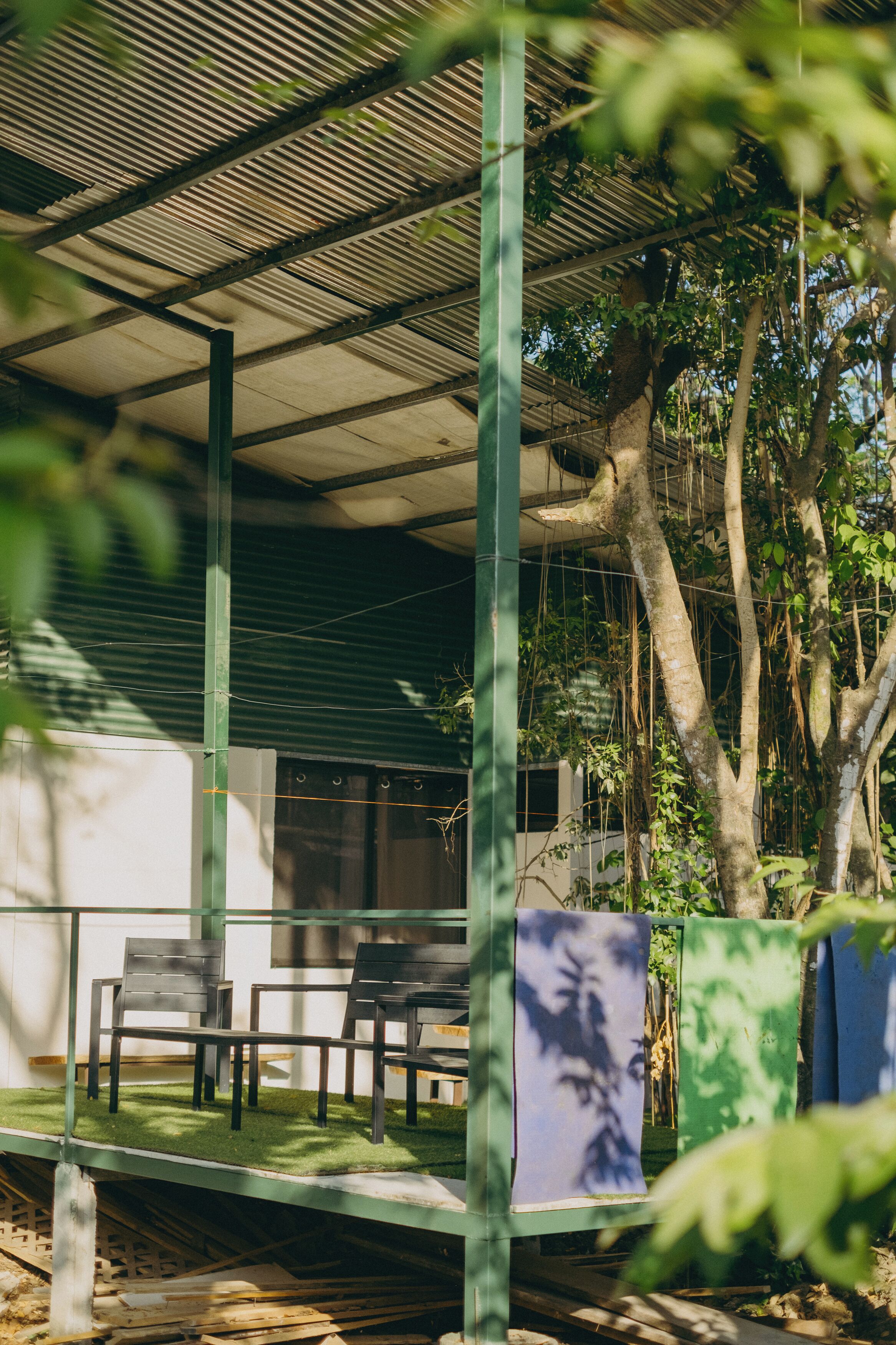 Un espace extérieur abrité, aménagé avec des chaises et des tables, et entouré d’arbres et de verdure.