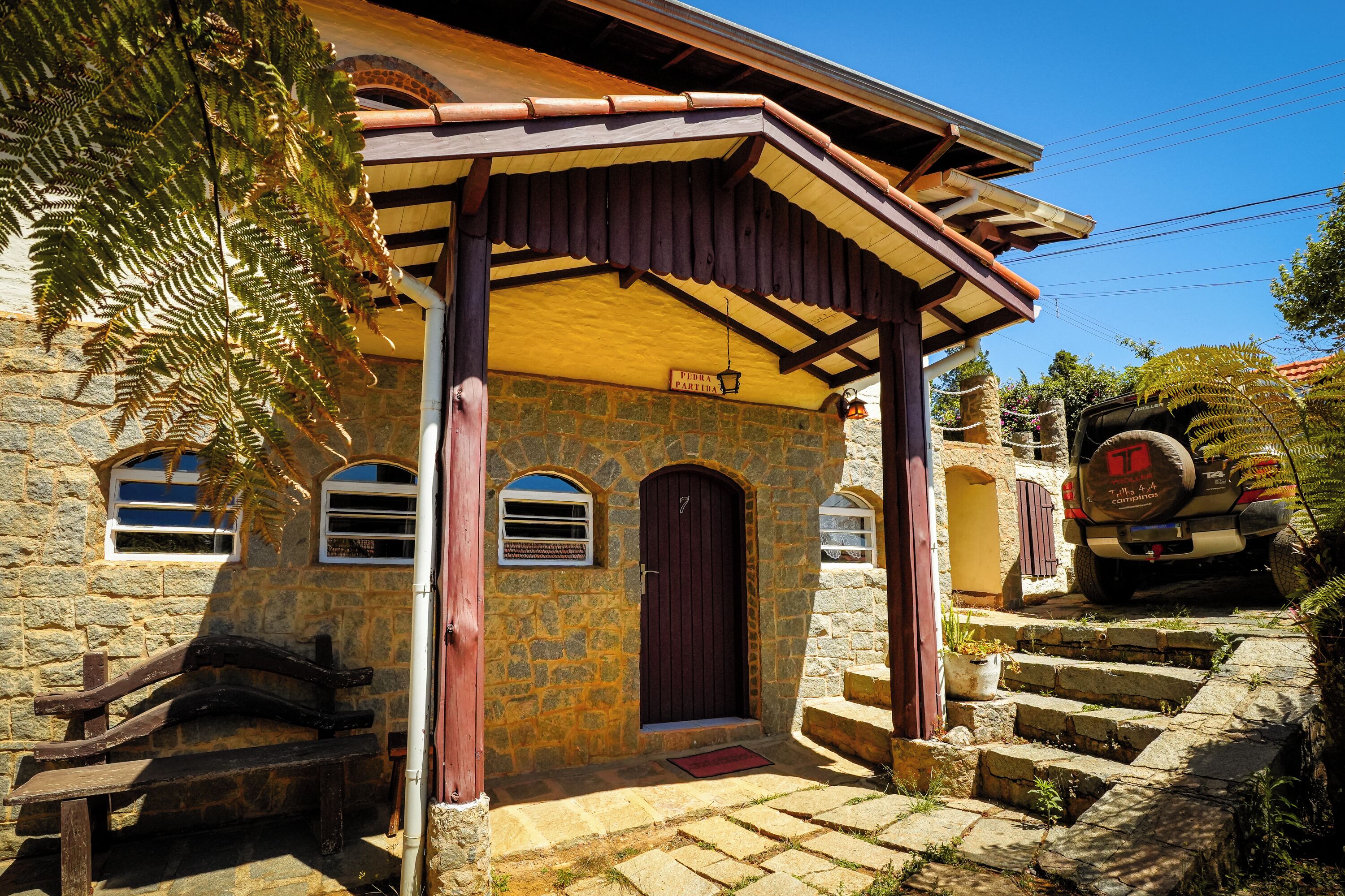 A stone building with a wooden porch, a red door, and a sign that reads "FERIA PARADA".