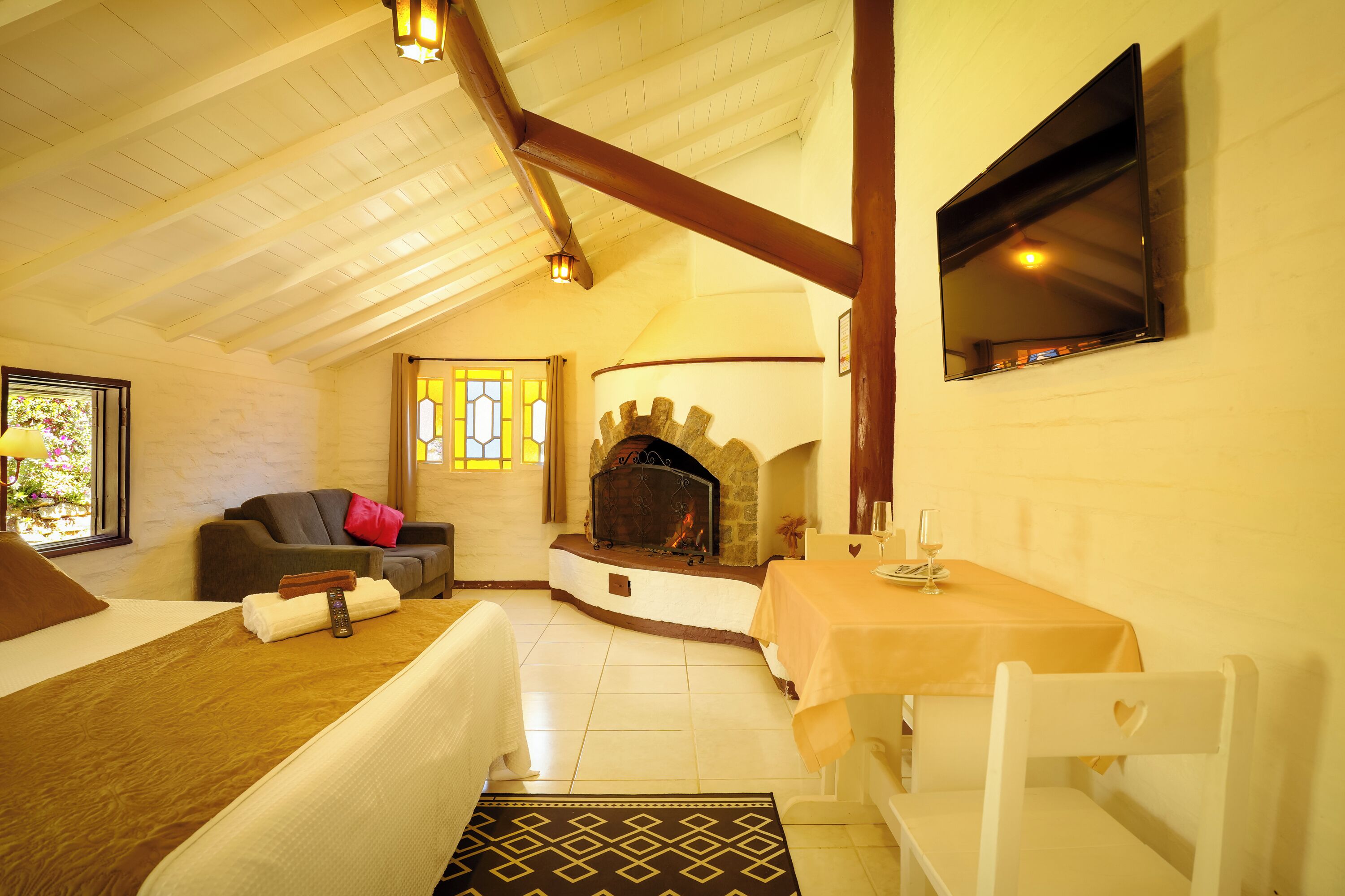 Una habitación acogedora con chimenea, un sofá, una mesa de comedor y un televisor en la pared.