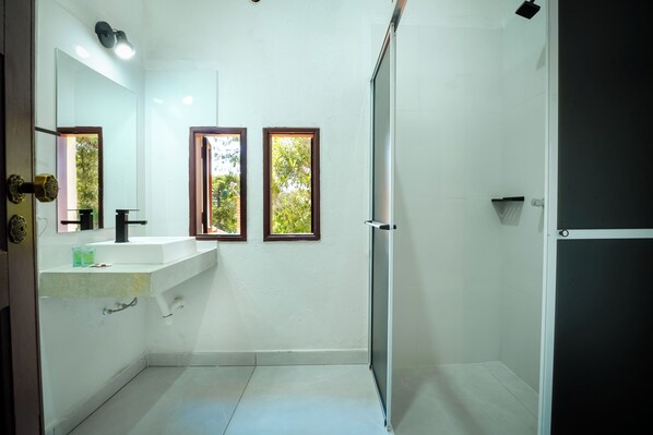 A modern bathroom with a white sink, mirror, and shower. - VELINN Pousada Dom Sossego (Monte Verde)