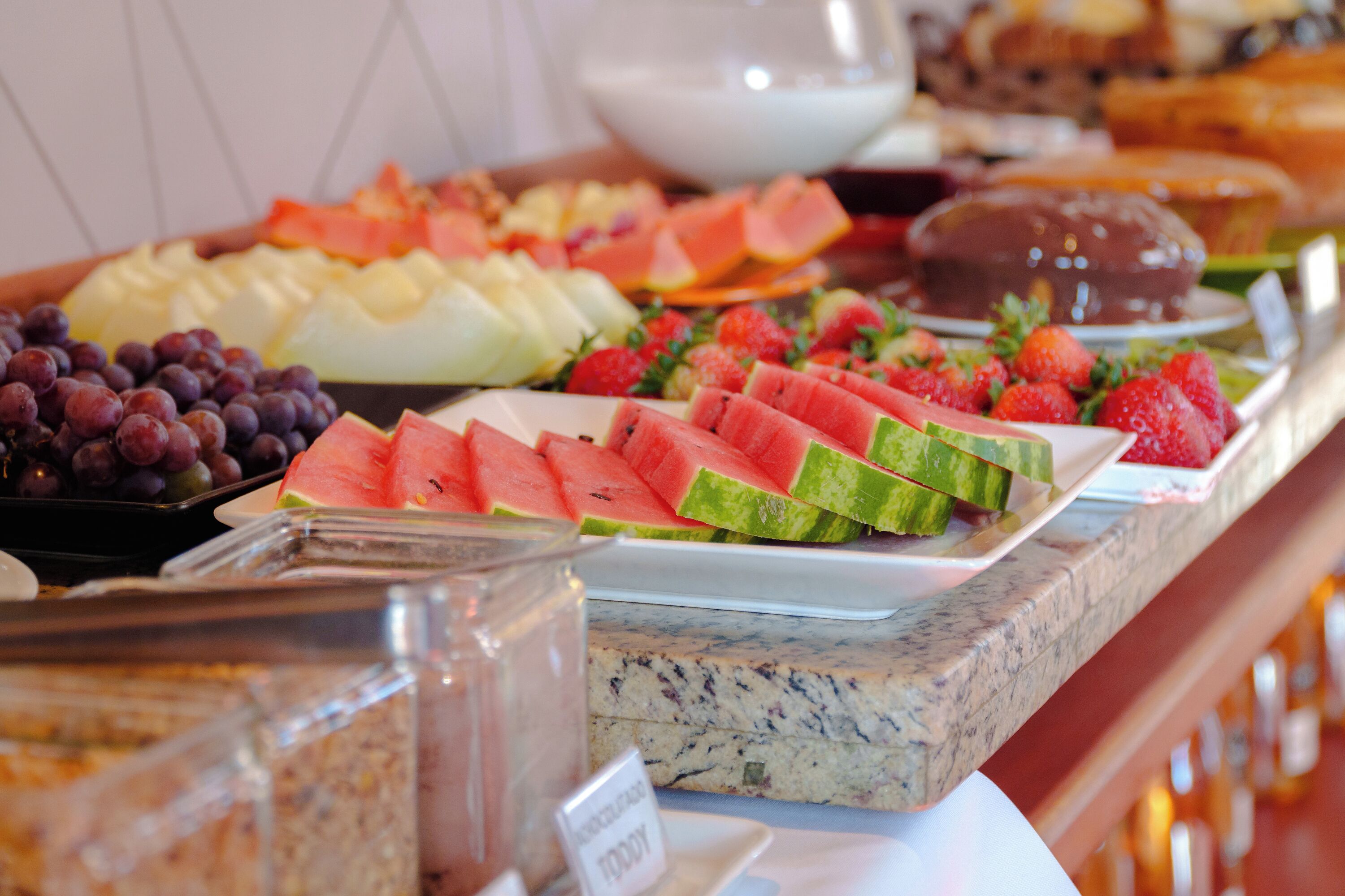 A buffet with various fruits and a chocolate dessert.