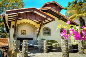 A building with a stone facade, a wooden roof, and a chain-link fence in front. - VELINN Pousada Dom Sossego (Monte Verde)