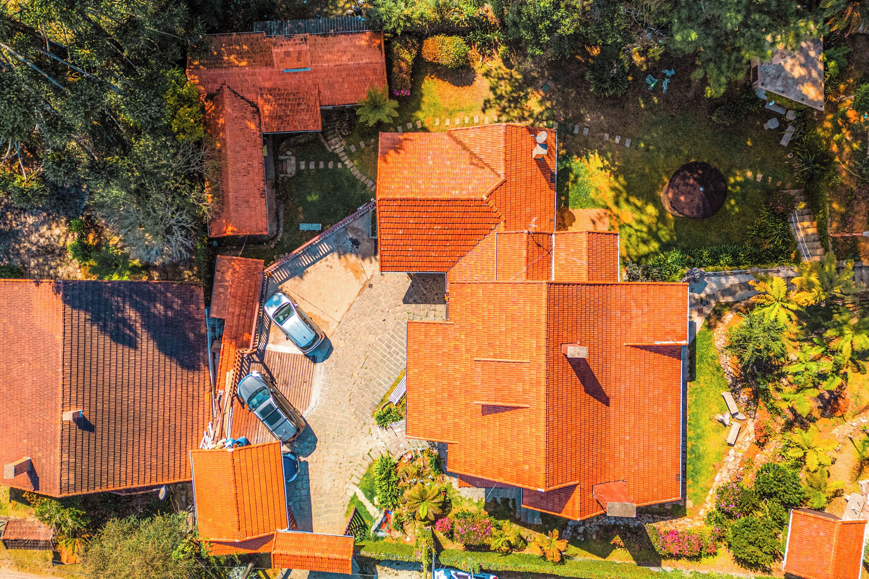 An aerial view of a residential area with multiple houses, a paved driveway, and a small garden area.