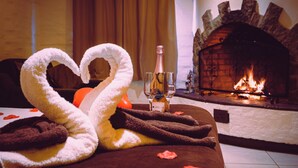 Een bed met twee handdoeken in de vorm van zwanen, een fles drank en glaasjes erop.