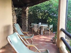 Relax in a serene outdoor space with a stone wall, wooden railing, and comfortable lounge seating.