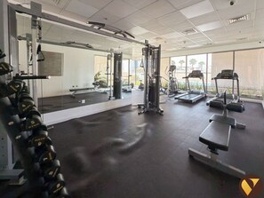 A gym with various exercise equipment, including dumbbells, a squat rack, and treadmills.
