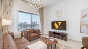 A modern living room with a large window, a flat-screen TV, and a sofa. - Jeewar Brand New Relaxing Pool Kids Area (Dubai)