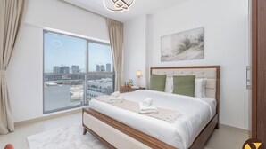 A modern bedroom with a large bed, a city view, and a minimalist decor. - Jeewar Brand New Relaxing Pool Kids Area (Dubai)