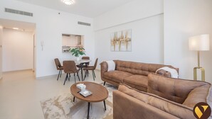 A modern living room with a brown leather sofa, a round coffee table, and a dining area with chairs and a table. - Jeewar Brand New Relaxing Pool Kids Area (Dubai)