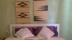 Ein Bett mit einem gemusterten Überwurf, einem weißen Kopfteil und zwei Kissen.