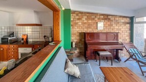 A compact living space with a kitchen, dining area, and a piano. - Surf-Check House - 3 min walk to the Beach (Playa del Hombre)