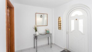 A hallway with a white door, a console table with a mirror, and a small window. - Surf-Check House - 3 min walk to the Beach (Playa del Hombre)