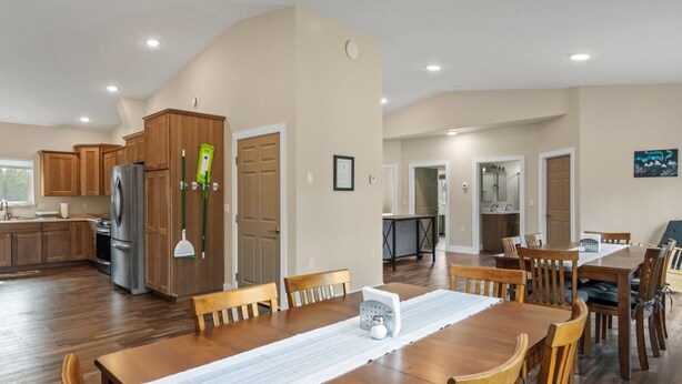 A spacious kitchen with wooden cabinets, a refrigerator, and a dining area with a wooden table and chairs. - Modern Alaskan Retreat (Soldotna)