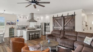 A modern kitchen with white cabinets, a central island, and a farmhouse-style barn door.