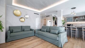 Una sala de estar moderna con un sofá seccional gris, piso de madera y una zona de cocina con barra.